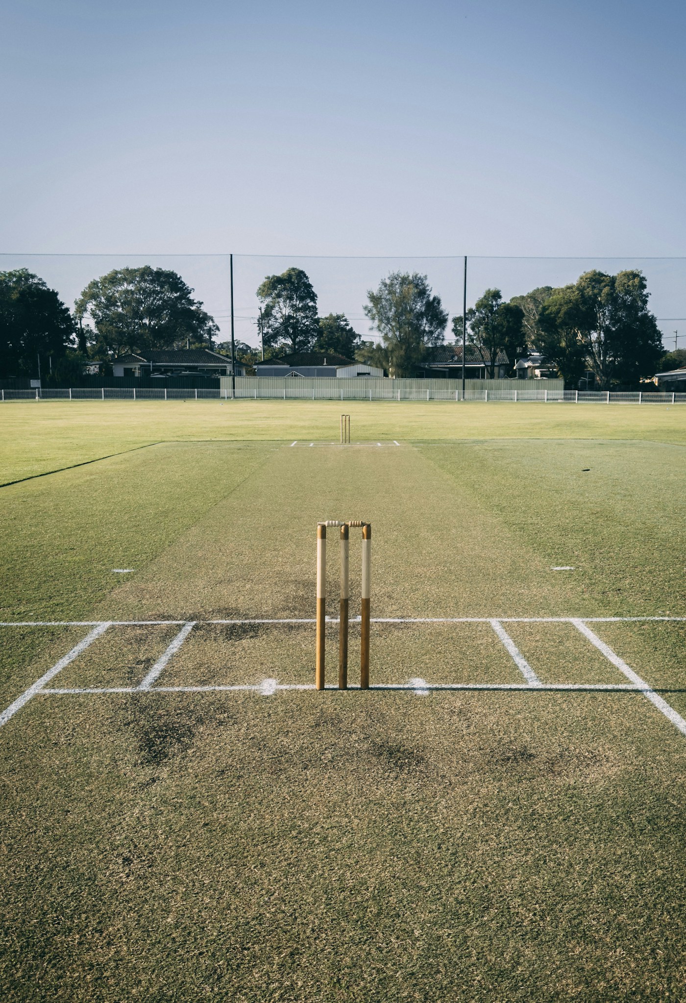 Stumps and marked crease on an open cricket ground